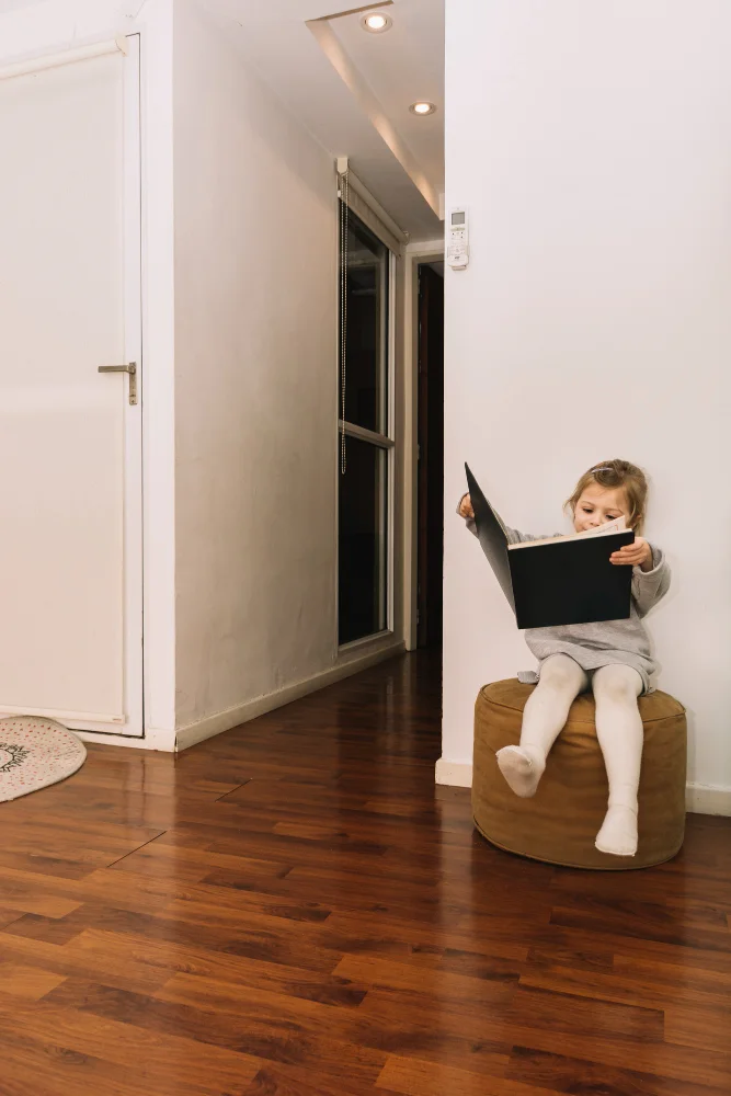 Child reading on polished blackbutt wood solid timber flooring in a family home